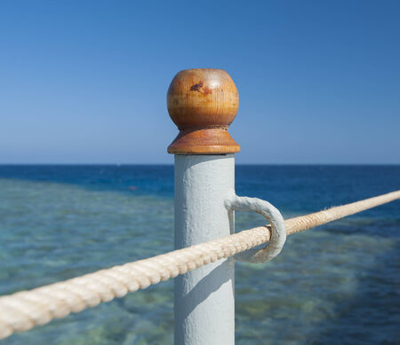 Abstract closeup detail of metal post with eyelet and rope handrailの写真素材