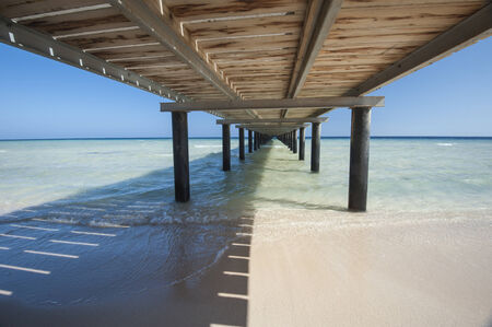 Wooden jetty structure going out to sea on tropical beach resortの写真素材