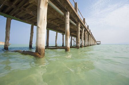Long wooden jetty in the sea from a tropical island lagoon on beachの写真素材