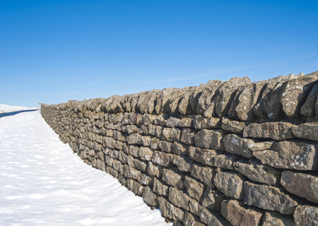 Dry stone wall in an english snow covered winter countryside rural landscapeの写真素材