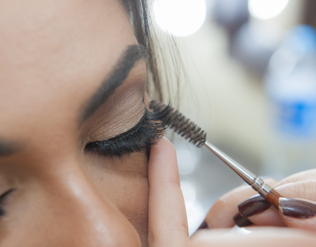 Closeup detail of womans eyelid and eyelash applying makeup mascara