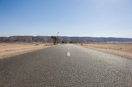 Closeup of a tarmac road surface going into the distance through the desertの写真素材