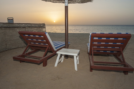 Sunrise at dawn over ocean at tropical hotel resort beach with sun loungersの写真素材