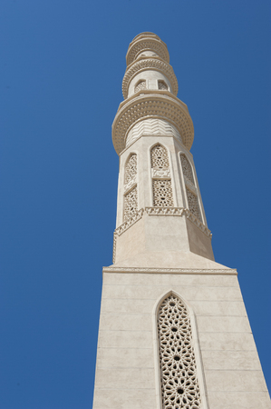 Large minaret of a muslim mosque against blue sky backgroundの写真素材