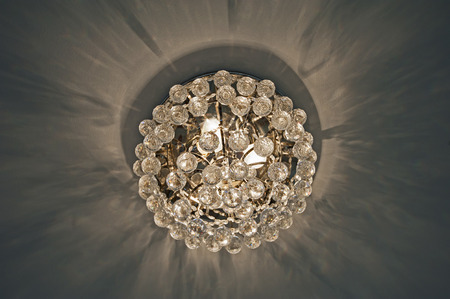 Ornate glass chandelier style ceiling light inside luxury apartment casting shadow