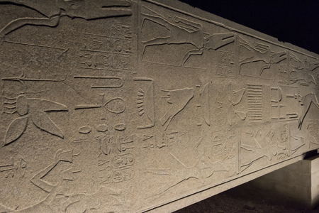 Tall stone ancient egyptian obelisk on side at Karnak Temple in Luxor lit up during night on black sky backgroundの写真素材