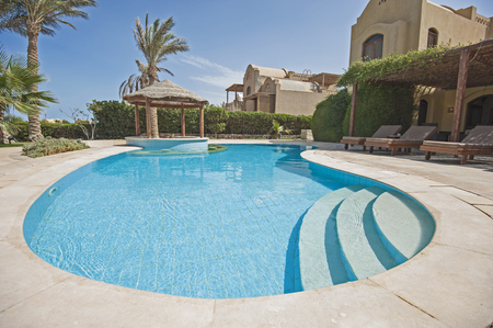 Luxury villa show home in tropical summer holiday resort with swimming pool bar and sun chairsの写真素材