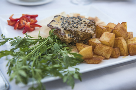 Closeup detail of beef fillet steak in pepper sauce at luxury restaurant with outdoor rable settingの写真素材