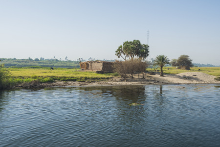 View across large wide river Nile in Egypt to riverbank through rural countryside landscapeの写真素材