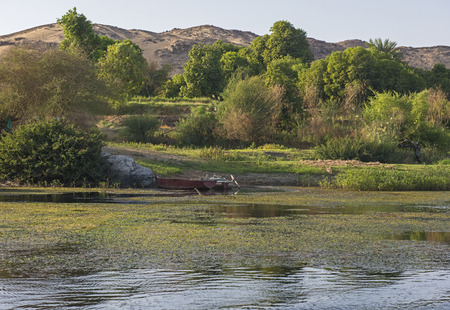 View across large wide river Nile in Aswan Egypt to riverbank through rural countryside landscape