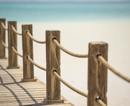 Wooden posts and rope railings on jetty over tropical sea with lagoonの写真素材