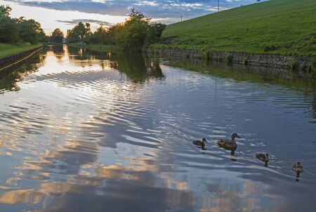 View of an English rural countryside scenery on British waterway canal during overcast cloudy day at sunset duskの写真素材