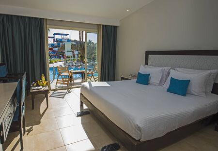 Double bed in suite of a luxury hotel room with terrace and pool viewの写真素材