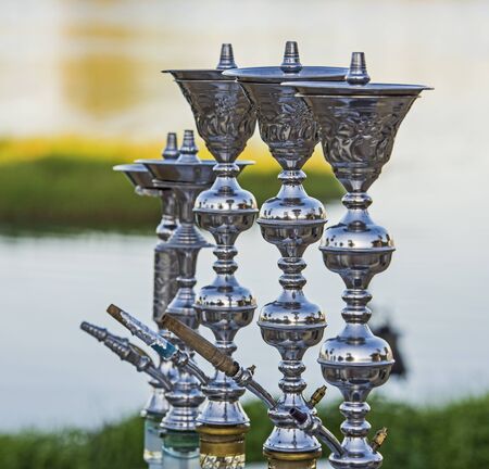 Large metal shisha water pipes in a row with river backgroundの写真素材