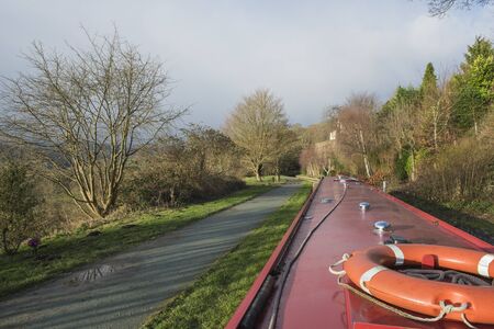 View from a narrowboat travelling in English rural countryside scenery on British waterway canal