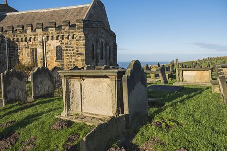 Old eroded church cemetary graveyard with rows of headstones and tombs in rural landscapeの写真素材