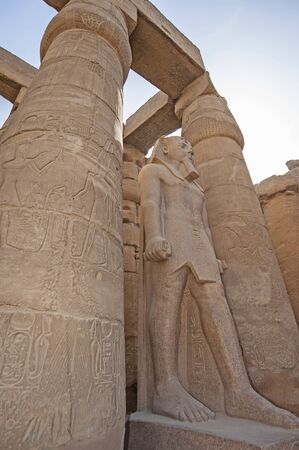 Large statue and hieroglypic carvings of Ramses II at the ancient egyptian Luxor temple with columns