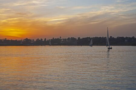 Landscape view of traditional egyptian felluca sailing boats on river Nile at dusk sunsetの写真素材
