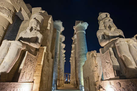 Large columns in hypostyle hall at ancient egyptian Luxor Temple lit up during nightの写真素材