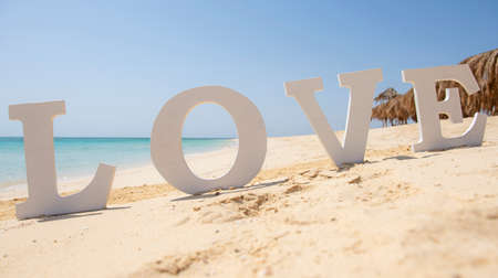 Closeup of romantic love sign on tropical island sandy beach paradise with ocean in backgroundの写真素材