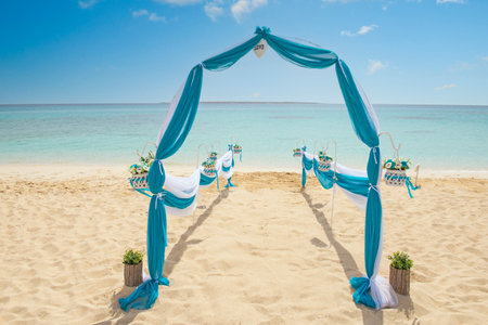 Setup of wedding day marriage aisle with drapes and arch on sandy tropical beach paradise to open ocean backgroundの写真素材