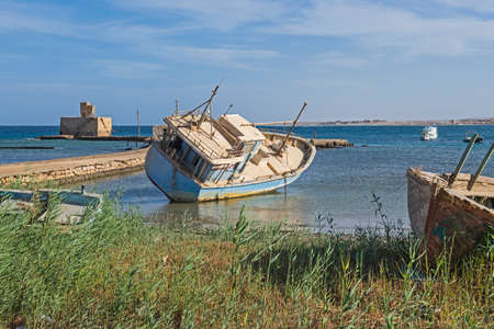 Old derelict small shpwreck boat abandoned on beach by coastの写真素材