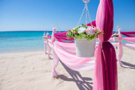 Setup of wedding day marriage aisle with drapes and arch on sandy tropical beach paradise to open ocean backgroundの写真素材