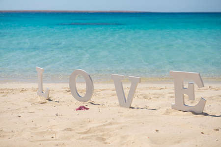 Closeup of romantic love sign on tropical island sandy beach paradise with ocean in backgroundの写真素材