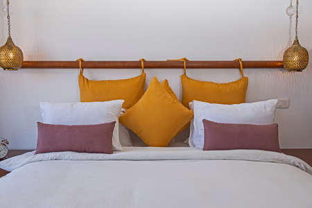 Interior design decor furnishing of luxury show home bedroom showing closeup of double bed with hanging lightsの写真素材