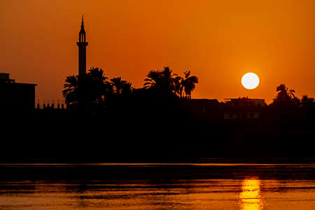 View across large wide river Nile in Egypt through rural countryside landscape with beautiful orange...