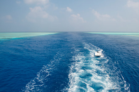 Panoramic scenic view of seascape over tropical ocean through channel in coral reef atoll with boat wakeの写真素材