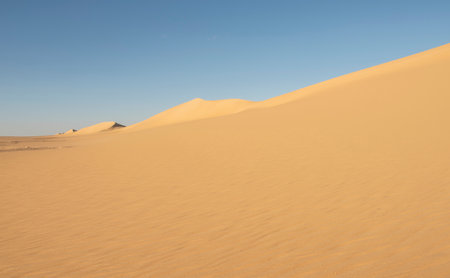 Landscape scenic view of desolate barren western desert in Egypt with Karaween large sand dunes against blue sky backgroundの写真素材