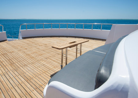Teak bow deck of a large luxury motor yacht with chairs sofa table and tropical sea view backgroundの写真素材