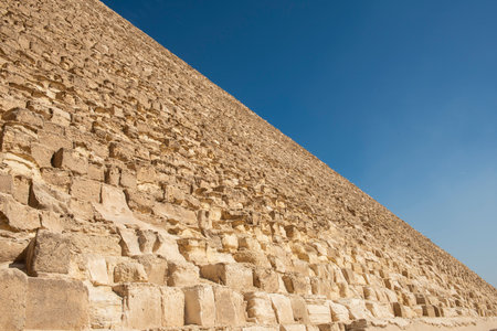Abstract view of side sloping wall on ancient egyptian stone pyramid tomb against blue sky...