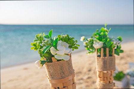 Closeup detail of flower plant bouquet decorations in holders wedding decoration with tropical blue ocean in backgroundの写真素材