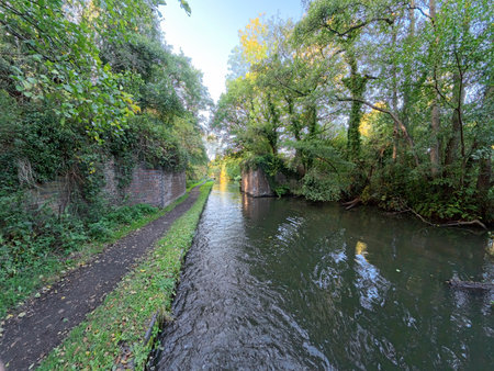 View of an English rural countryside scenery on British waterway canal with blue sky and reflection...