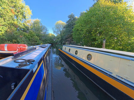 Narrowboat moored up in English rural countryside scenery on British waterway canal with blue sky in autumn fallの写真素材