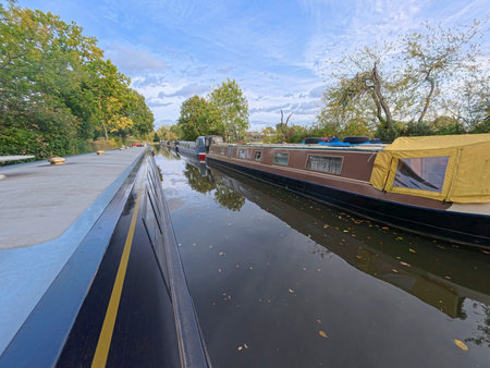 Narrowboats moored up in English rural countryside scenery on British waterway canal with blue sky in autumn fallの写真素材