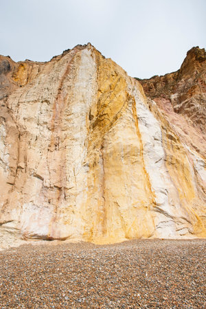 Panoramic landscape view of beautiful shades in multi-colored sand cliffs at Alum Bay Isle of Wight coastal seaside resort town with rocky shingle beachの写真素材