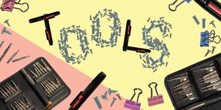 desktop with screwdrivers, hardware, clothespins. Blank for the designer with the inscription tools. isolated on yellow backgroundの写真素材
