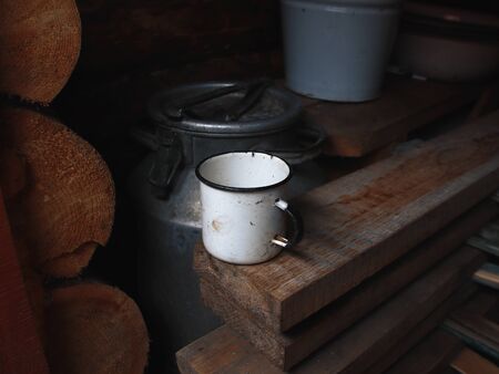 Photo of rural life in the Belarusian Outback. metal mug in the bath on the background of boards and a can of water in the bath on the background of boards and a can of waterの写真素材