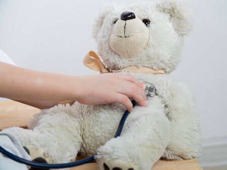 Cute kid boy playing doctor with plush toy at home. child boy playing doctor and curing plush toy indoors. isolated on whiteの写真素材