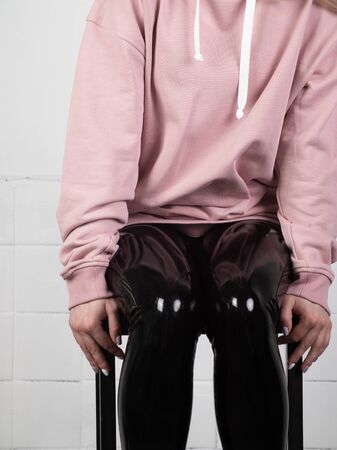 legs of a girl in latex tight pants. a girl in fashionable clothes is sitting on a chairの写真素材