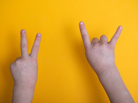 isolated child hand shows the number two on yellow backgroundの写真素材