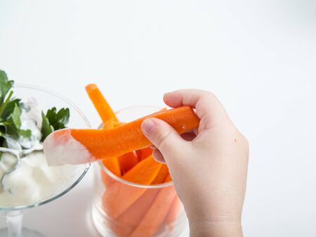 the child takes a glass of sliced fresh carrots. the concept of healthy eating for children and adults. white backgroundの写真素材