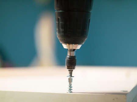 furniture screws and a screwdriver against the background of assembled furniture in the apartment.の写真素材