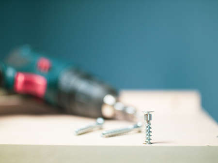 furniture screws and a screwdriver against the background of assembled furniture in the apartment.の写真素材