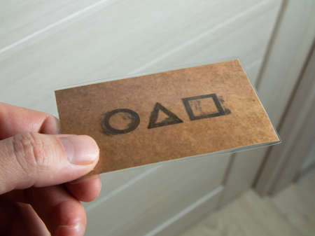 Moscow, Russia- 03 Novemnver 2021: Man hand holding a squid game card invitation near his door.のeditorial素材