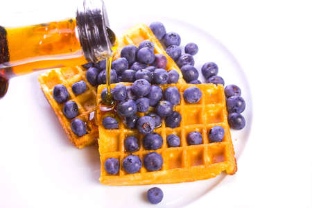 Maple syrup poured on blueberry covered wafflesの写真素材