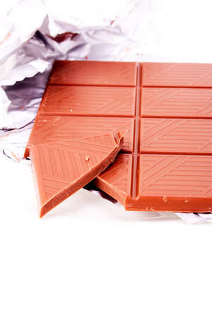 Milk chocolate bar with foil wrapping on whiteの写真素材